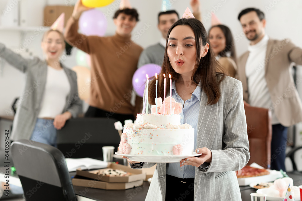 Young woman with Birthday cake making wish at party in office Young woman with Birthday cake making wish at party in office