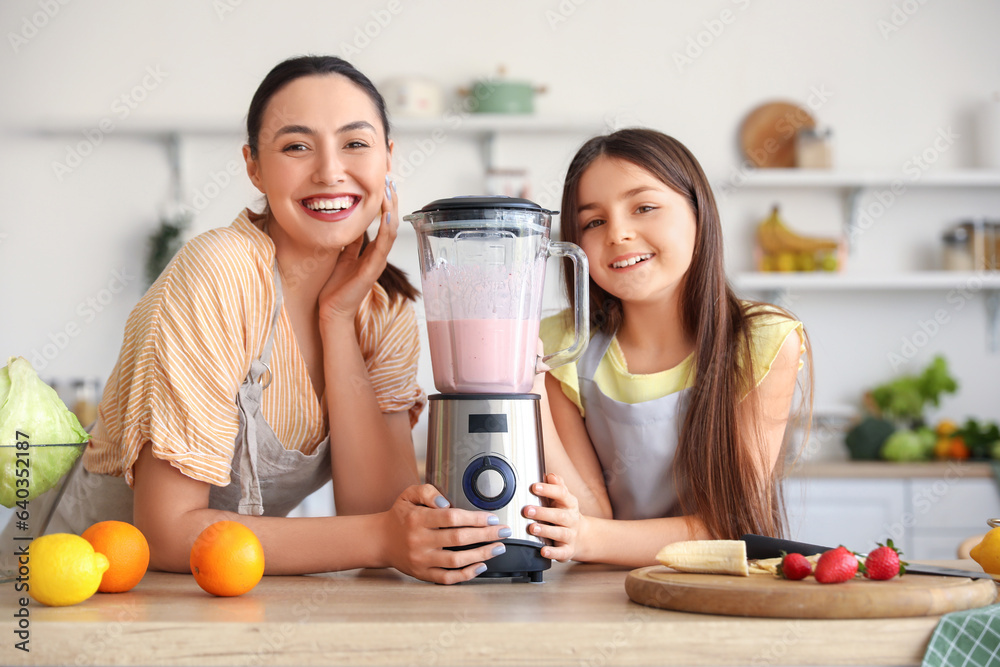 Little girl and her mother making smoothie with blender in kitchen Little girl and her mother making smoothie with blender in kitchen