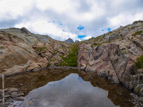Panoramic view of small glacier pond in the Mercantour National Park in the Valley of Marvels near Tende, Provence-Alpes-Côte d'Azur Alpes-Maritimes, France. High mountain ridges in French Alps