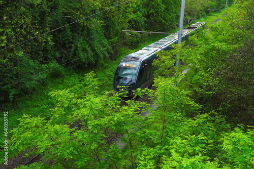 Top view of a passing modern tram in the green park area of the city
