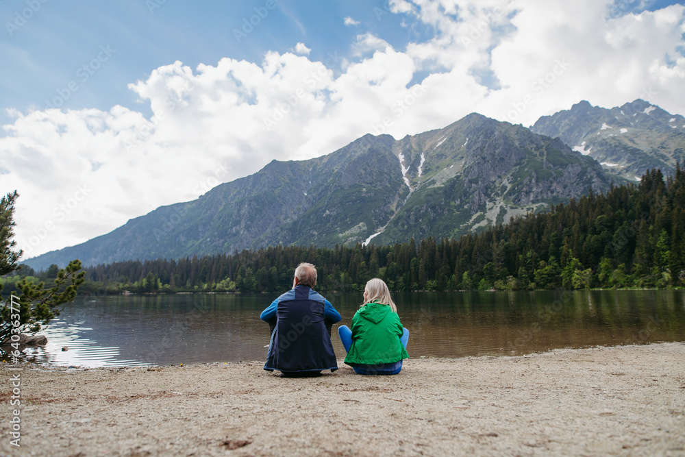 Rear view of senior couple resting after hiking in autumn mountains.