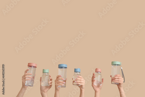 Female hands with bottles of cold water on beige background