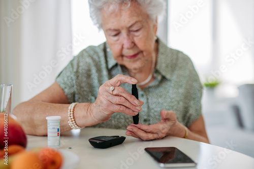 Close up of diabetic senior patient checking her blood sugar level with fingerstick testing glucose meter.