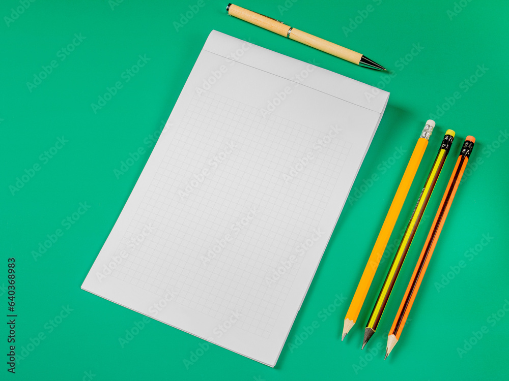 Office theme.Open notebook,pencils and pen on a green background Office theme.Open notebook,pencils and pen on a green background