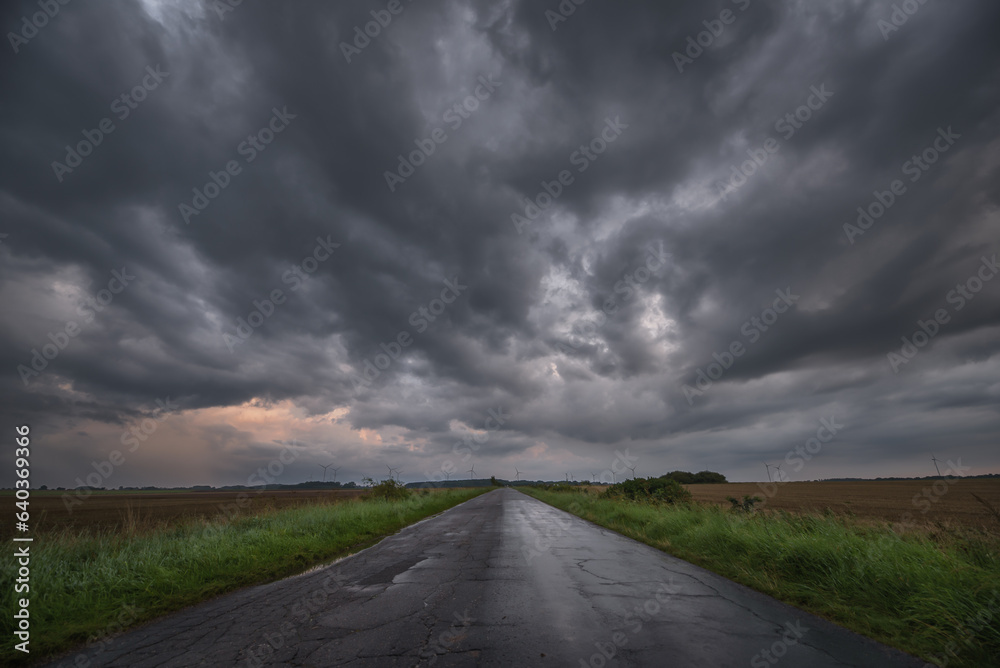 
WEATHER - Dramatic black rain clouds over fields and country road

