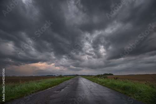  WEATHER - Dramatic black rain clouds over fields and country road 