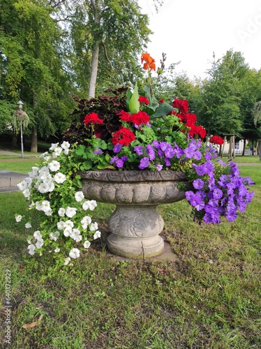 Blühendes Blumen Arrangement in einer großen Vase aus Beton in Parklandschaft