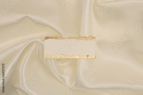 Gold glitter empty canvas paper frame label on beige silk fabric background. Abstract copy space texture. photo