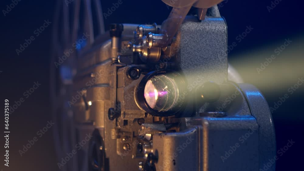 Close up view of old vintage movie projector playing film. 16mm retro projector. The concept of old film or cinema. beam of light illuminates in dark.