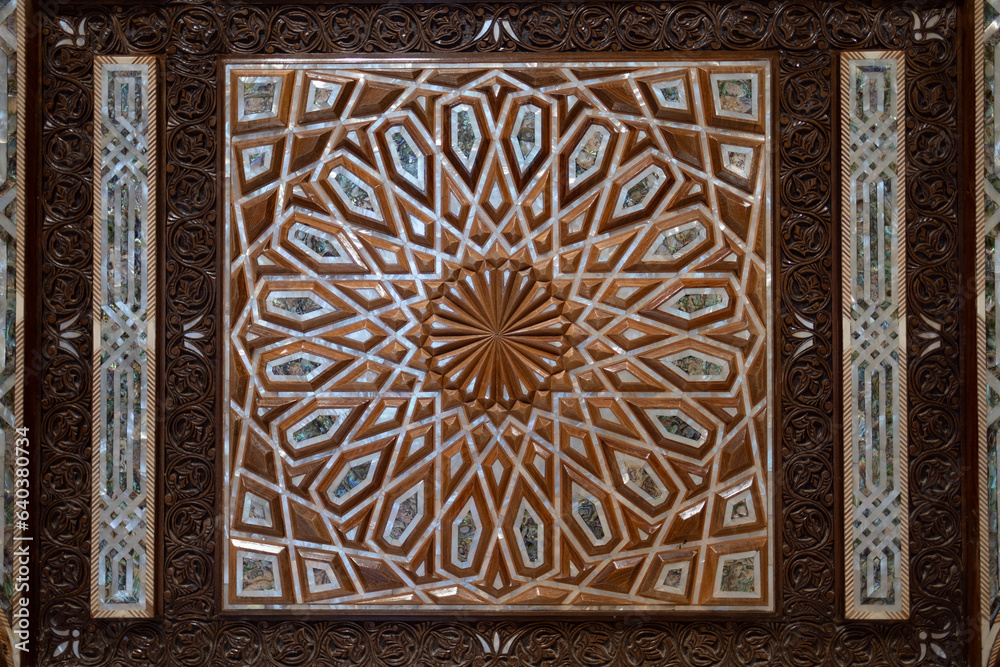 On the door of a mosque's entrance, a design of carved wood, bone, and mother of pearl. The geometric design is a strong example of Islamic art and design.