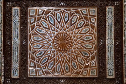 On the door of a mosque's entrance, a design of carved wood, bone, and mother of pearl. The geometric design is a strong example of Islamic art and design.