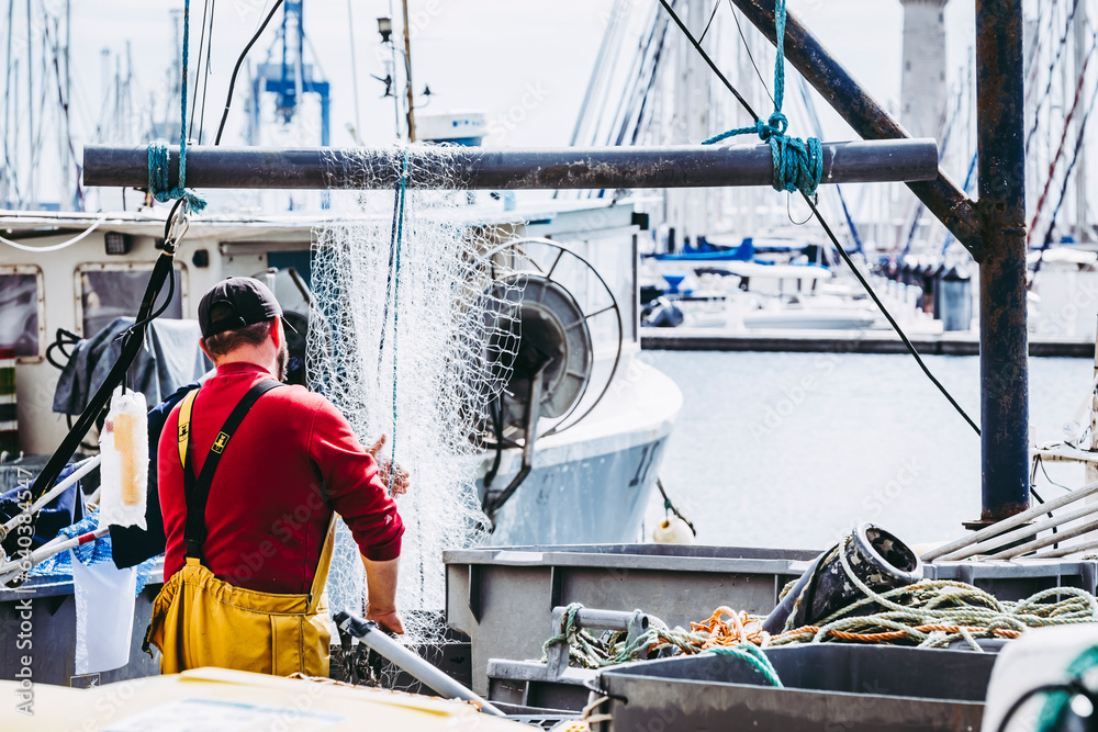Pêcheur en train de nettoyer et ranger les filets de pêche sur le port