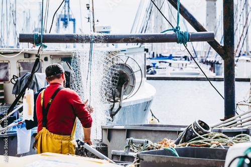 Obraz na płótnie Pêcheur en train de nettoyer et ranger les filets de pêche sur le port w salonie