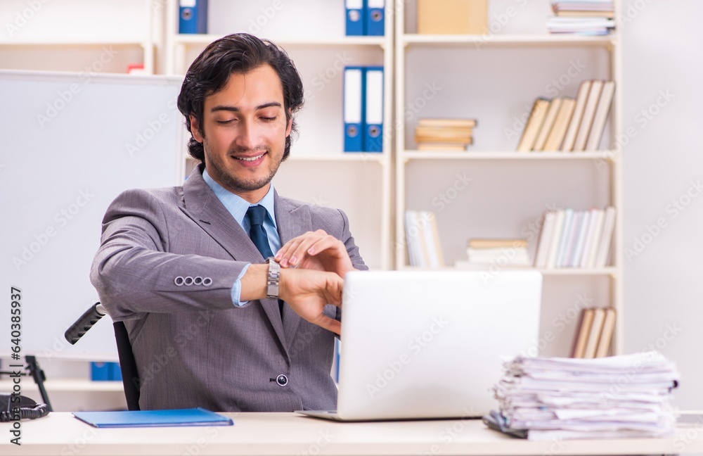 Young handsome employee in wheelchair at the office Young handsome employee in wheelchair at the office