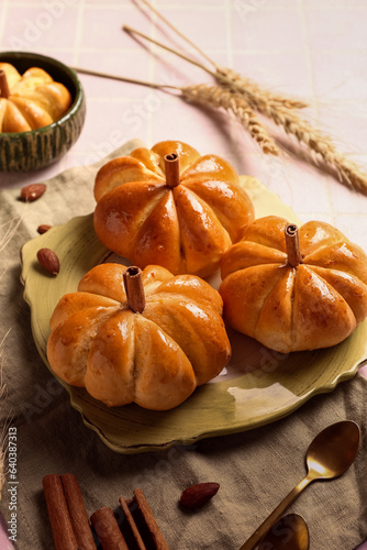 Plate with tasty pumpkin shaped buns on pink tile background