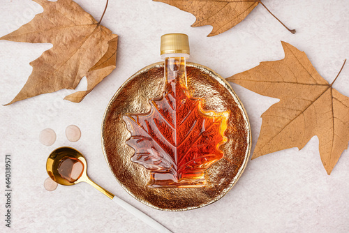 Bottle of tasty maple syrup on light background photo