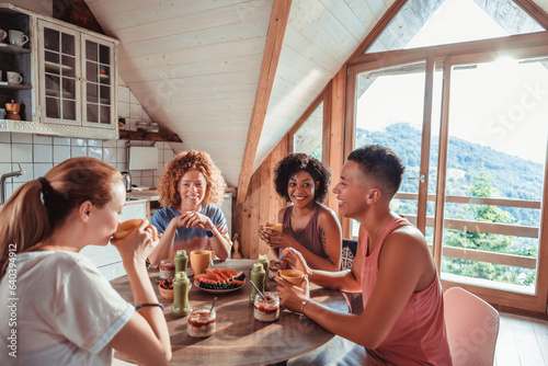 Young and diverse gorup of female friends having breakfast together in a cabin in the forest photo