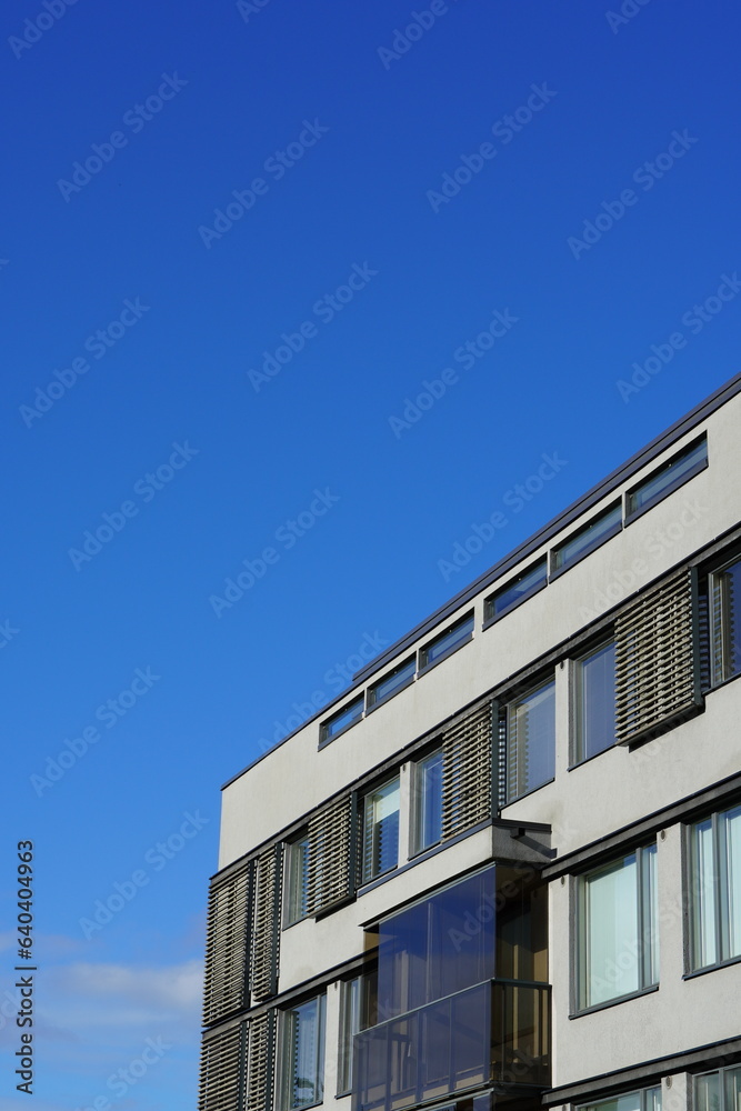 View to white appartment building with wooden details towards blue sky. Tallinn, Estonia