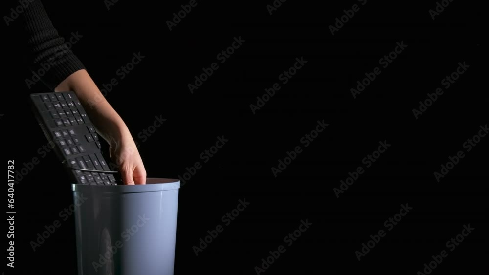 Hands with keyboard by bin. A view of female hands throw the distroyed