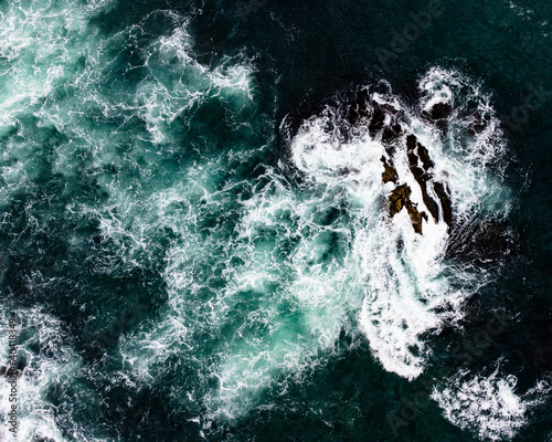 Picture from above of waves hiting rocks in the sea