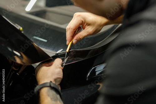 Car wrapping specialist wraps a car parts with adhesive foil