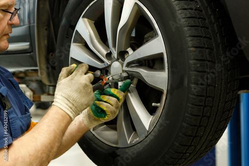 Close up of mechanic removes a wheel from car © AvokadoStudio