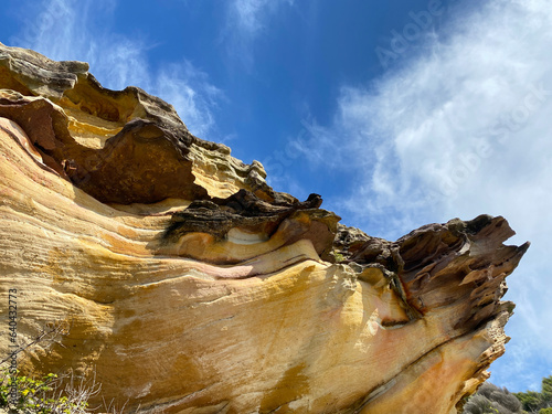 Formation rocheuse sous un ciel bleu. Rocher ocre et brun ondulant au soleil. Règne minéral sur les côtes. Minerai sculpter par le vent. Paysage côtier. Géologie canyon.