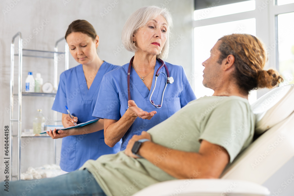 Fototapeta premium Gastroenterologist doctor consulting man in clinic. Patient having medical exam with doctor on illness from stomach discomfort.