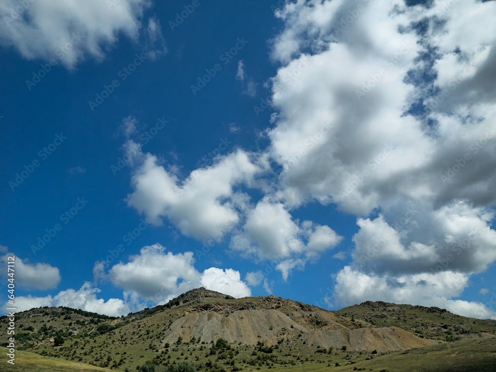Serene Horizon: Majestic Mountain Landscape with Peaceful Blue Sky and Rolling Countryside