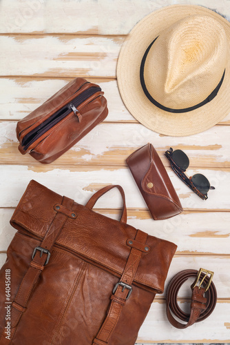 Leather backpack, hat and accessories on a white table. Stylish brown leather accessories close-up. View from above.
