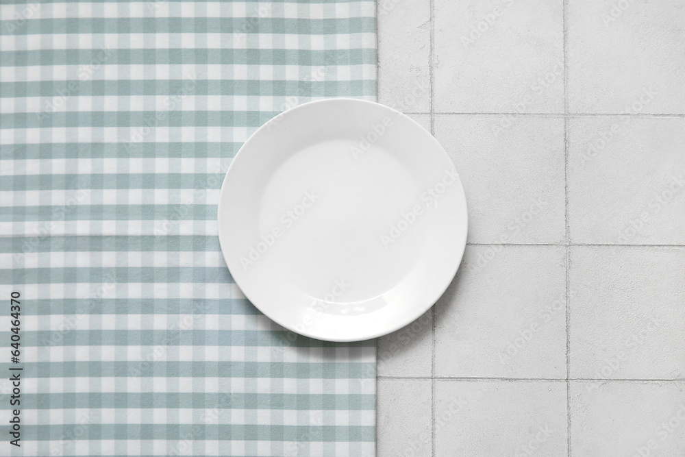 Clean plate and napkin on white tile background Clean plate and napkin on white tile background