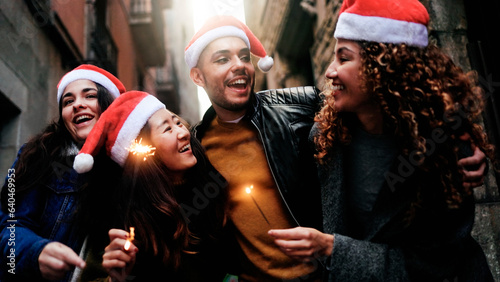 Happy diverse friends celebrate Christmas party with sparkler fireworks outdoors - Multi-ethnic group of people having fun during December holidays - Focus on transgender gay person