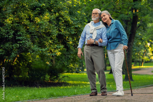 Senior man with walking cane and mature woman in park. Space for text