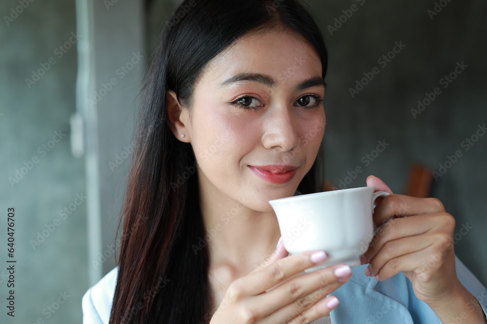 Portrait of smiling happy cheerful beautiful pretty Asian woman drinking coffee or tea in a cafe. Portrait of smiling happy cheerful beautiful pretty Asian woman drinking coffee or tea in a cafe.