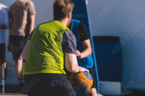 Athletes play basketball, teenage team play street basketball, players on the outdoor basketball court venue, sports team during the game, playing match game in a summer sunny day