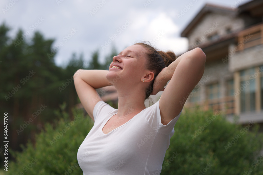 Portrait of happy young woman standing in the garden outside her luxury home and smiling and relax outside 
