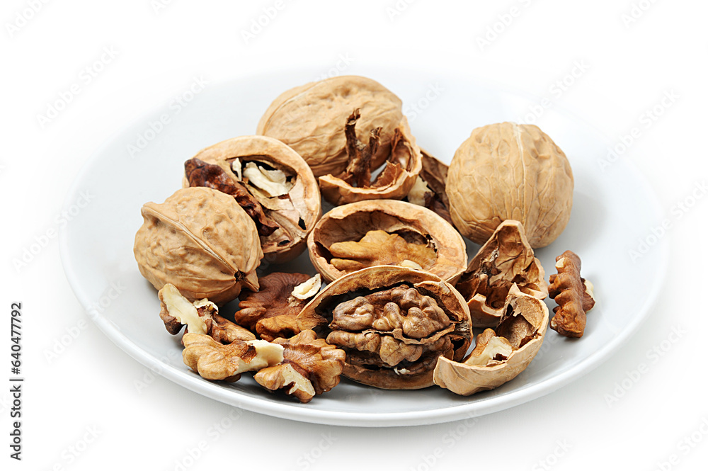 Walnuts on white plate, Walnuts kernels and shells Walnuts on white plate, Walnuts kernels and shells