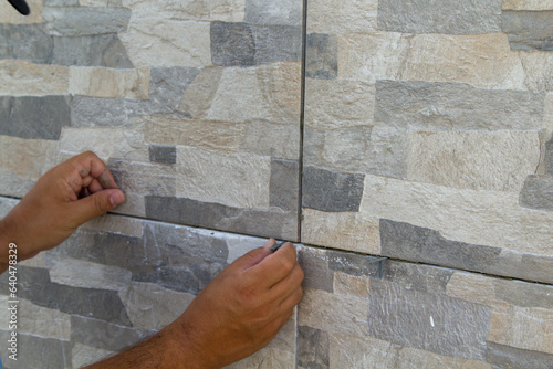 Image of the hands of a tiler mason inserting shims into freshly laid tiles. Do-it-yourself work, renovation and installation of a house floor. photo