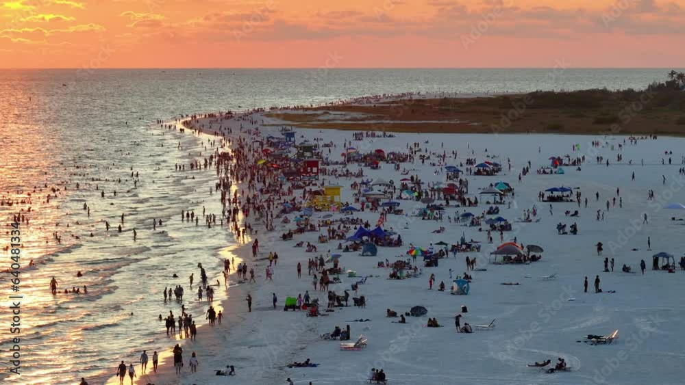High angle view of crowded Siesta Key beach in Sarasota, USA. Many people enjoing vacations time swimming in ocean water and relaxing on warm Florida sun at sundown High angle view of crowded Siesta Key beach in Sarasota, USA. Many people enjoing vacations time swimming in ocean water and relaxing on warm Florida sun at sundown