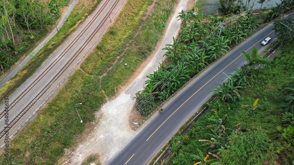 Aerial drone view of highway and railroad tracks among green trees and mountains