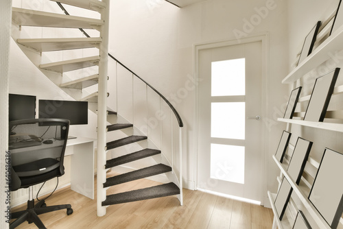 a room with some stairs and a computer on the desk next to an open door that leads to another room photo
