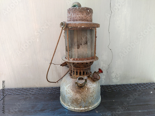 an ancient petromax lamp lit with kerosene fuel in a rusty and damaged condition
 photo