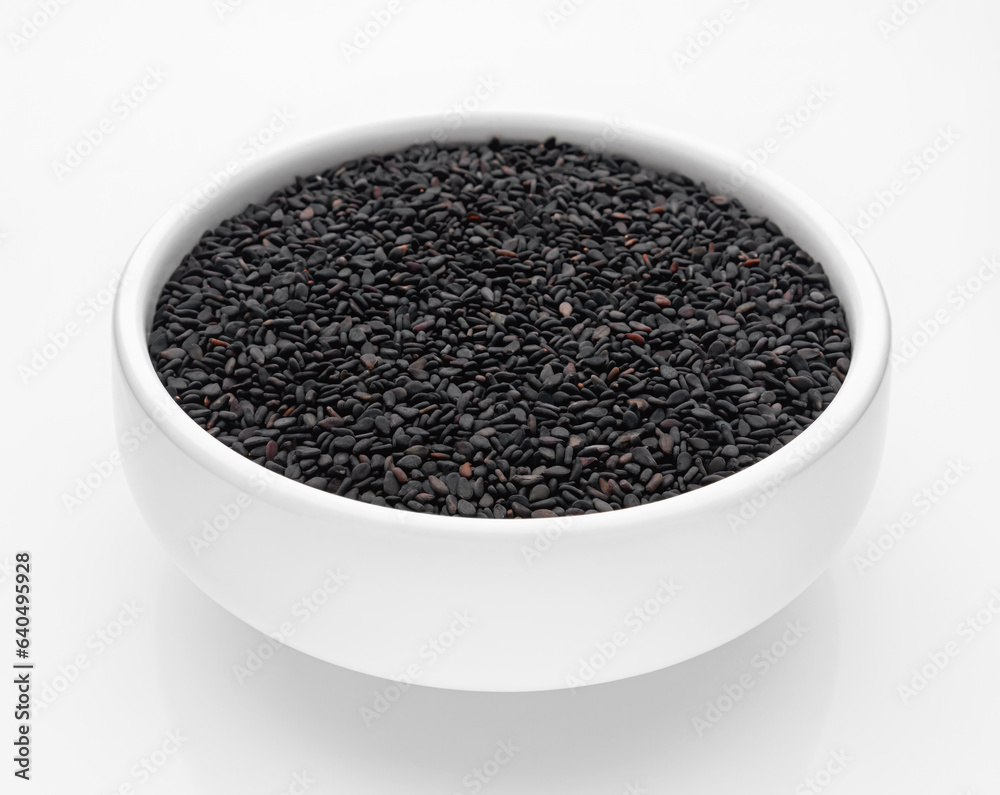 Black sesame seeds in a white bowl on a white background. Isolate. Selective focus. Close-up. Black sesame seeds in a white bowl on a white background. Isolate. Selective focus. Close-up.