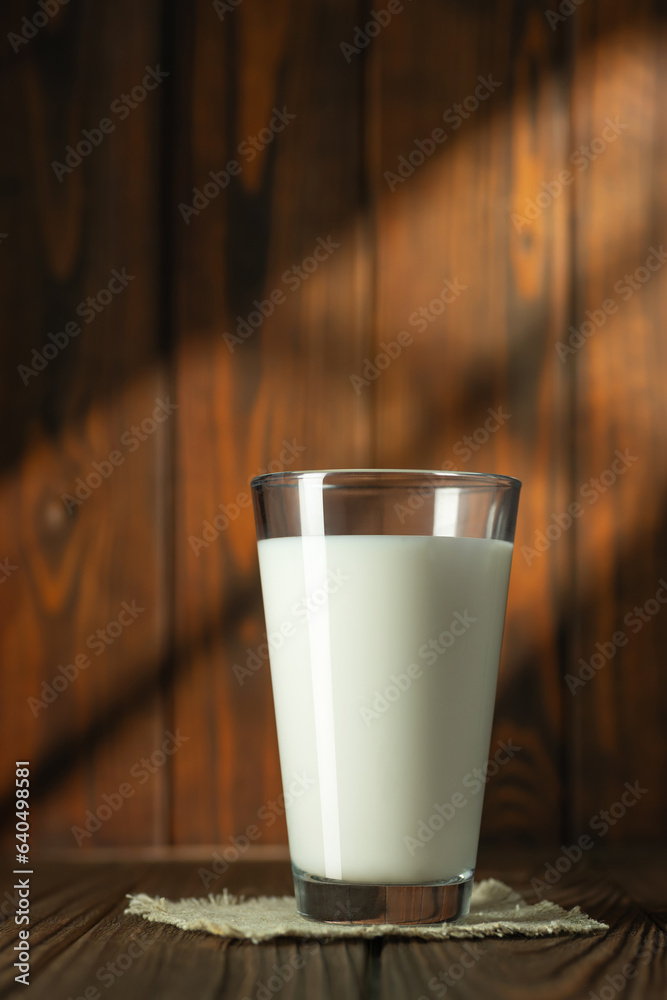 glass of milk on wooden table with sun rays glass of milk on wooden table with sun rays