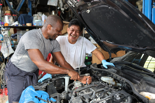 Group of car mechanic men in half uniform checking maintenance a car service at repair garage station. Worker holding wrench and fixing breakdown vehicle. Concept of car center repair service.