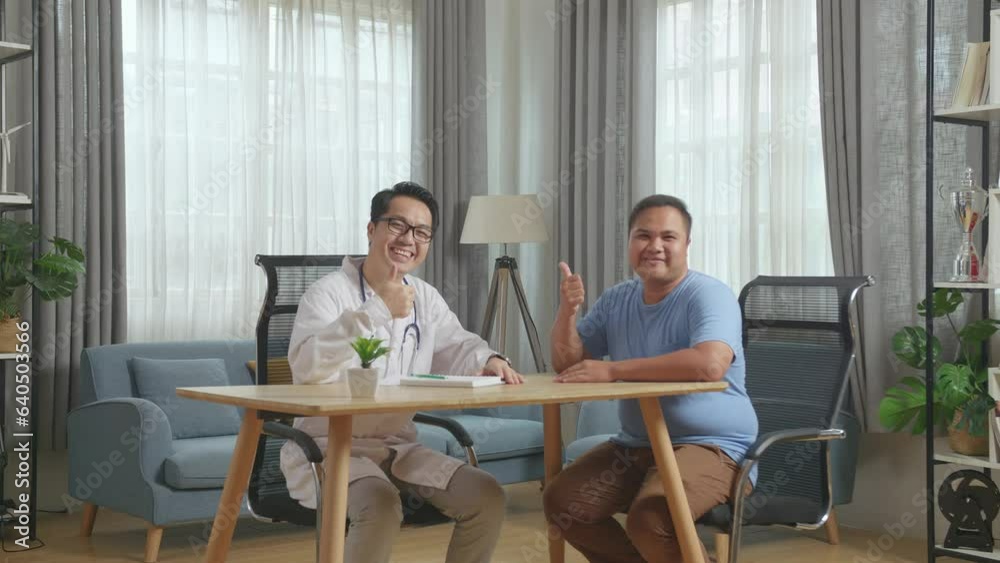 Asian Male Doctor With A Fat Male Patient In Clinic. Writing Prescription, Sitting At Desk, Smiling And Showing Thumbs Up Gesture To Camera
Asian Male Doctor With A Fat Male Patient In Clinic. Writing Prescription, Sitting At Desk, Smiling And Showing Thumbs Up Gesture To Camera