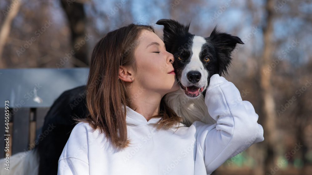 Caucasian woman hugging her dog Border Collie while sitting on a bench in autumn park. Caucasian woman hugging her dog Border Collie while sitting on a bench in autumn park.