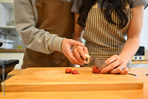 Cropped shot of young couple cutting strawberries on kitchen counter, preparing a healthy breakfast together