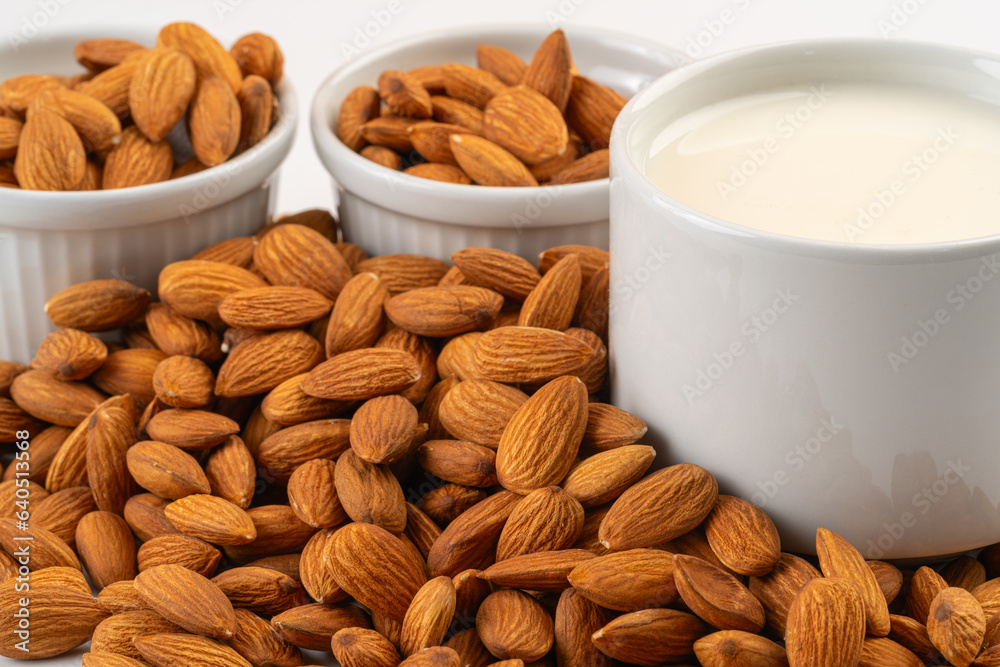 Pile of almonds and a cup of almond milk Pile of almonds and a cup of almond milk