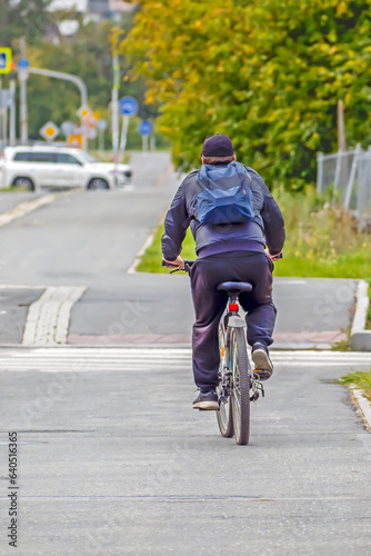 A man rides a bicycle along an alley on an autumn day